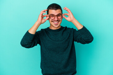Young caucasian man isolated on blue background excited keeping ok gesture on eye.