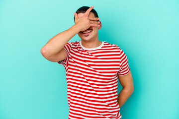 Young caucasian man isolated on blue background covers eyes with hands, smiles broadly waiting for a surprise.