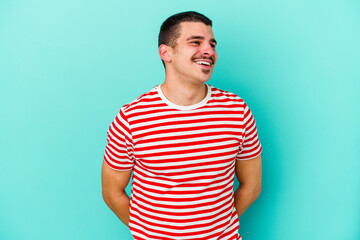 Young caucasian man isolated on blue background relaxed and happy laughing, neck stretched showing teeth.