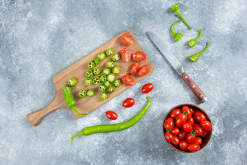 Sliced jalapeno peppers and tomatoes on wooden board