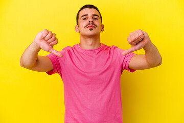 Young caucasian cool man isolated on yellow background showing a dislike gesture, thumbs down. Disagreement concept.