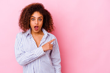 Young african american woman isolated on pink background pointing to the side