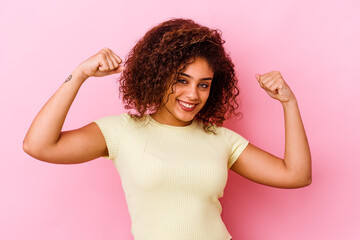 Young african american woman isolated on pink background showing strength gesture with arms, symbol of feminine power