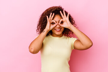 Young african american woman isolated on pink background showing okay sign over eyes