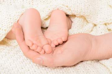 Baby feet on male hand with soft background, close-up