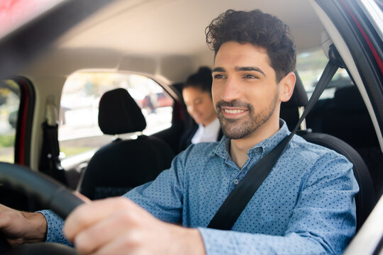 Taxi Driver With Passenger At Back Seat.