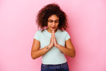 Young african american woman isolated on pink background praying, showing devotion, religious...