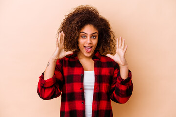 Young african american woman isolated on beige background celebrating a victory or success, he is surprised and shocked.