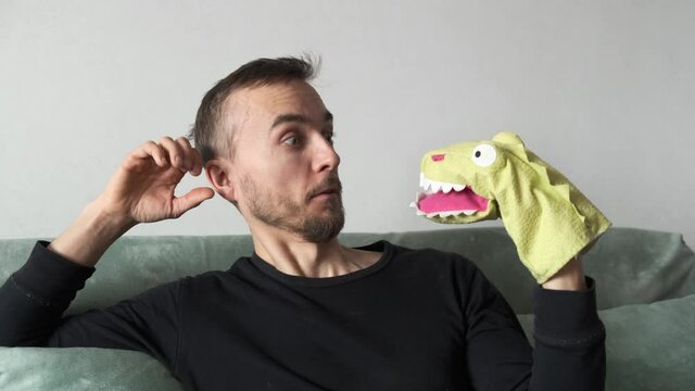 Strange man talking with puppet toy dragon. Crazy conspiracy theorist with reptiloid alien. Concept of talking to yourself, self psychotherapy or comic image of psychotherapist.