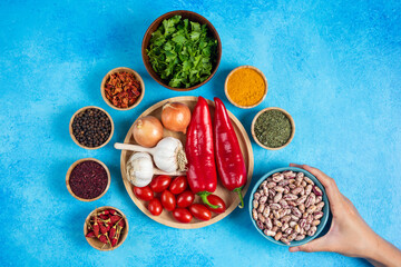 Variety of spices, vegetables and raw beans on blue background