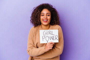 Young African American woman holding a Girl power placard isolated on purple background laughing and having fun.