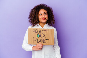 Young African American woman holding a girl power placard isolated on purple background dreaming of achieving goals and purposes