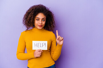 Young African American woman holding a Help placard isolated on purple background showing number one with finger.