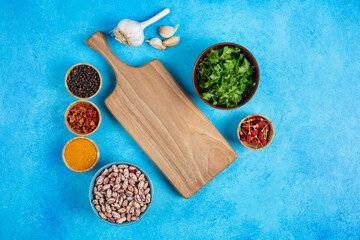 Variety of spices, vegetables and raw beans on blue background