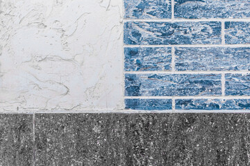 Part of modern building facade with dark black and white tiles texture and brick blue wall with abstract patterned background