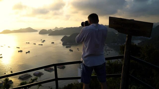 Man taking photo of amazing Ha Long Bay in Vietnam during sunset