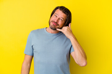 Fototapeta premium Middle age caucasian man isolated on yellow background showing a mobile phone call gesture with fingers.