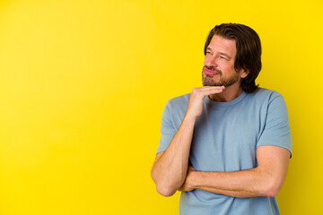 Middle age caucasian man isolated on yellow background looking sideways with doubtful and skeptical expression.