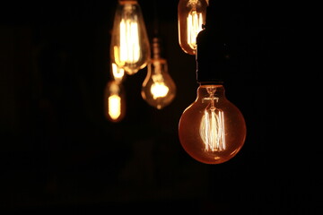 Isolated dark objects. Burning bulbs. Different vintage bulbs on black background. Crowded, low...