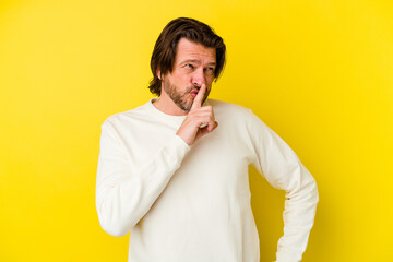 Fototapeta premium Middle age caucasian man isolated on yellow background keeping a secret or asking for silence.