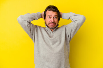 Middle age caucasian man isolated on yellow background touching back of head, thinking and making a...