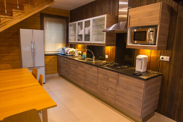 Kitchen interior in brown tones. Kitchen interior with wood furniture. Concept -  furniture is made of elite wood species. Dining room in a country house. Dining room in a country hotel.
