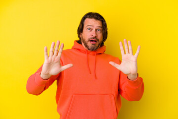 Middle age caucasian man isolated on yellow background being shocked due to an imminent danger