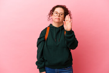 Young student woman with Down syndrome isolated on pink background standing with outstretched hand showing stop sign, preventing you.