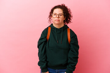 Young student woman with Down syndrome isolated on pink background screaming very angry and aggressive.