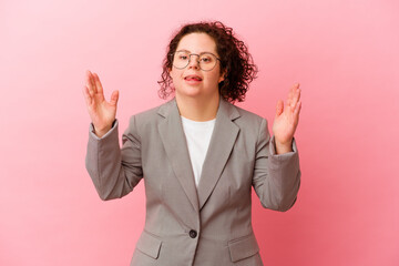 Business woman with Down syndrome isolated on pink background receiving a pleasant surprise, excited and raising hands.