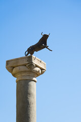 Bull statue on a pillar with blue sky in the background