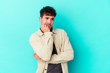 Young caucasian man isolated on blue background biting fingernails, nervous and very anxious.