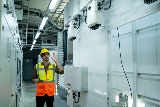 Portrait of electrician engineer use tablet computer taking notes at control room in factory.