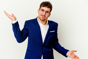 Young business caucasian man isolated on white background makes scale with arms, feels happy and confident.