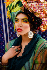 Fototapeta na wymiar beauty bright woman with creative make up, many shawls on head like cubian, ethno look closeup