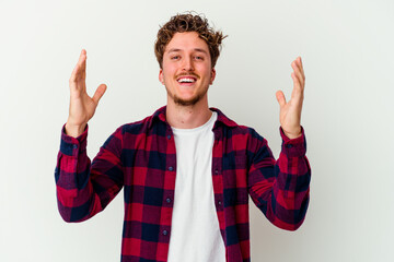 Naklejka premium Young caucasian man isolated on white background receiving a pleasant surprise, excited and raising hands.