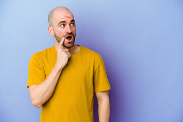 Young caucasian bald man isolated on purple background looking sideways with doubtful and skeptical expression.