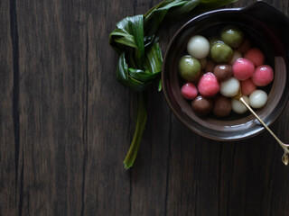 Tang Yuan (Glutinous Rice Balls) for DongZhi (Winter Solstice Festival). Colorful tang yuan flatlay on wooden table, dark food photography. Pink, Chocolate, Matcha Rice Balls Still Life.