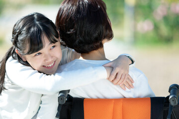 車椅子に座る祖母に抱きつく孫娘