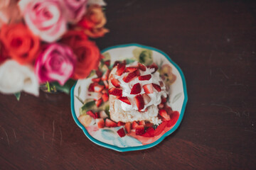 Strawberry Shortcake with strawberries, whipped cream, and angel food cake next to a vase of roses