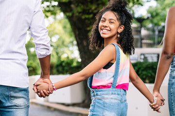 Fototapeta premium Little girl enjoying a walk outdoors with her parents.