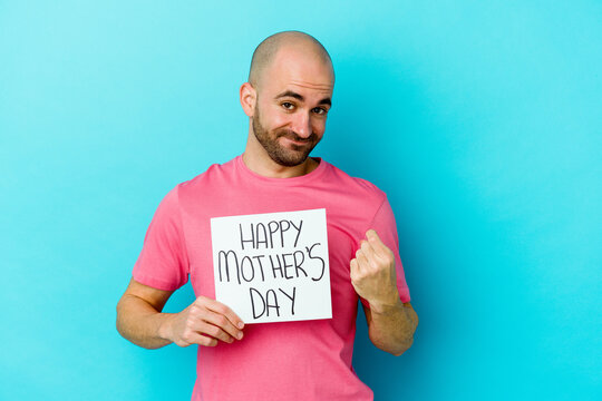 Young caucasian bald man holding a happy mothers day placard isolated on blue background pointing with finger at you as if inviting come closer. - Powered by Adobe