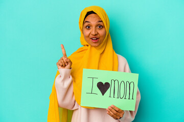 Young caucasian woman holding a I love mom isolated on pink background having some great idea, concept of creativity.