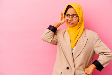 Young business muslim woman isolated on pink background touching back of head, thinking and making a choice.