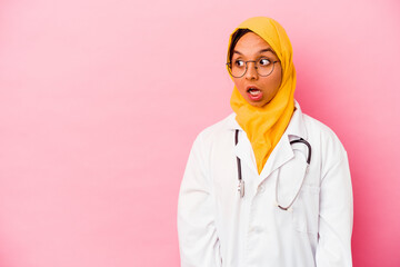 Young doctor muslim woman isolated on pink background being shocked because of something she has seen.