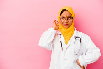 Young doctor muslim woman isolated on pink background touching back of head, thinking and making a choice.