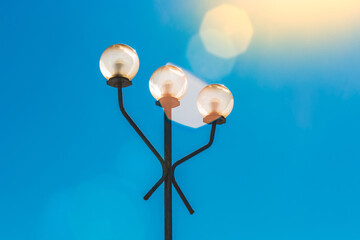 Street lighting element, lantern during the day in sunlight with glare against a blue sky