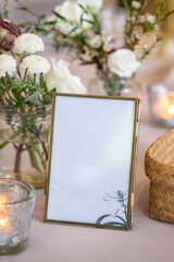 empty frame in white for text with romantic table decoration in restaurant, flower vest and candle on the table.