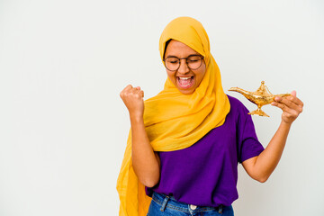 Young muslim woman holding a lamp isolated on white background raising fist after a victory, winner...