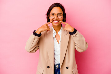 Young business mixed race woman isolated on pink background smiles, pointing fingers at mouth.